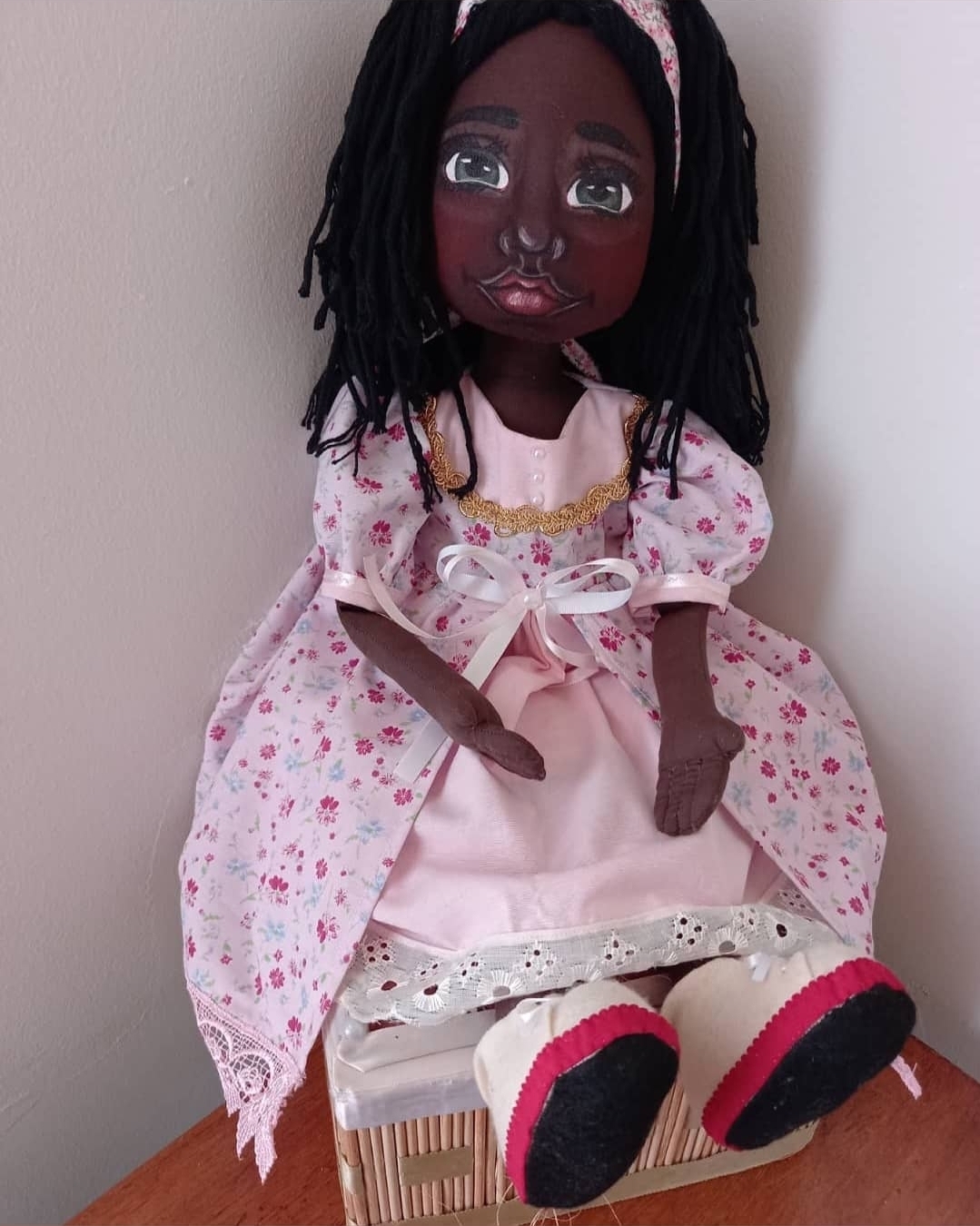 Boneca artesanal negra com vestido rosa floral